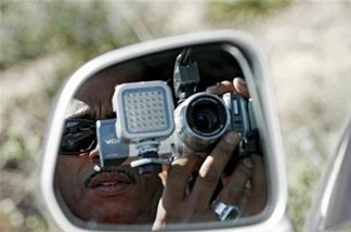 In this March 16, 2008, file photo, paparazzi Craig Williams, of Hollywood.TV, is seen through the side mirror during a stake out near Britney Spears' house in Los Angeles. Newly signed legislation would increase penalties for actions that include taking photos and video of a child without consent and in a harassing manner.