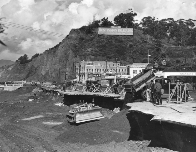 1938: People walk along the flooded L.A. River near the Dayton Avenue Bridge. In the background, a railroad bridge hangs in a twisted heap after one of the pilings has collapsed. (Photograph courtesy of the Los Angeles Public Library)