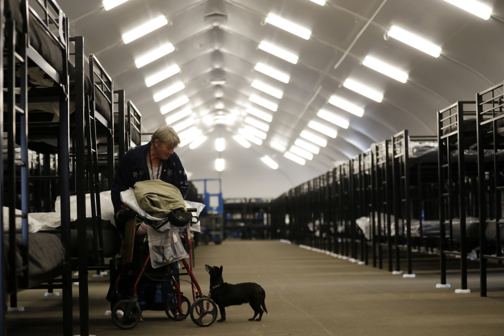 San Diego Homeless Tents Verna Vasbinder prepares her her new bunk in the city's new Temporary Bridge Shelter for the homeless as her dog, Lucy Lui, looks on Friday, Dec. 1, 2017, in San Diego. The first of three shelters opened Friday, which will eventually provide beds for up to 700 people, as the city struggles to control a homeless crisis gripping the region.