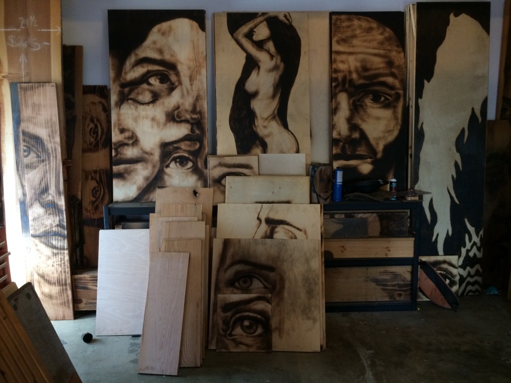Aronson’s work looks like charcoal drawings from a distance, but he actually chars the wood with flame to create a similar look. Aronson’s work looks like charcoal drawings from a distance, but he actually chars the wood with flame to create a similar look.
