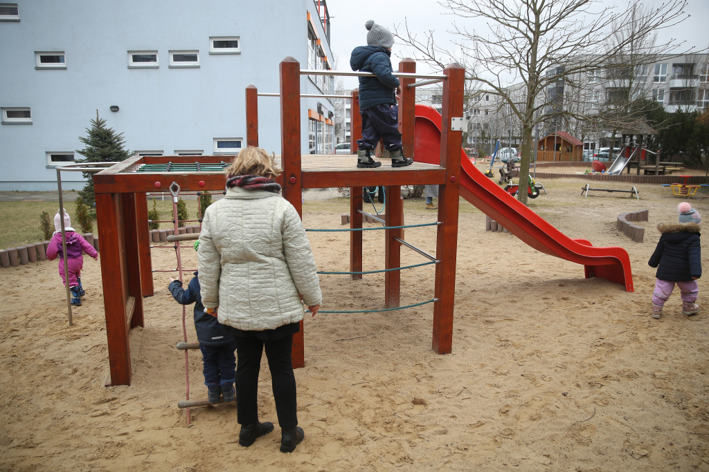 Family Minister Visits Day Care And Senior Care Facilities A nursery school teacher oversees children playing on a playground at the