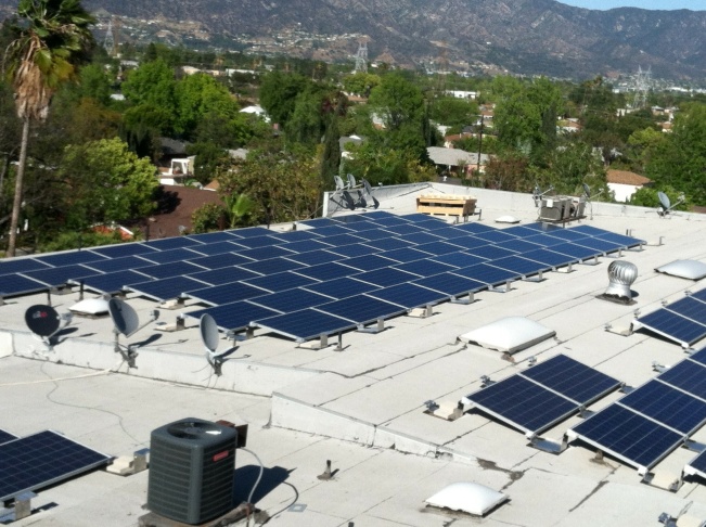 Workers install solar panels on the roof of the North Hollywood apartment complex participating in the program that lets businesses sell solar power from large-scale rooftop arrays to the L.A. Department of Water and Power.