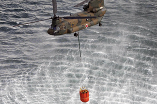 This aerial shot shows a Japanese Self Defence Force's CH-47 Chinook helicopter holding more than seven tonnes water each with large buckets from the sea near Natori in Miyagi prefecture on March 17, 2011.