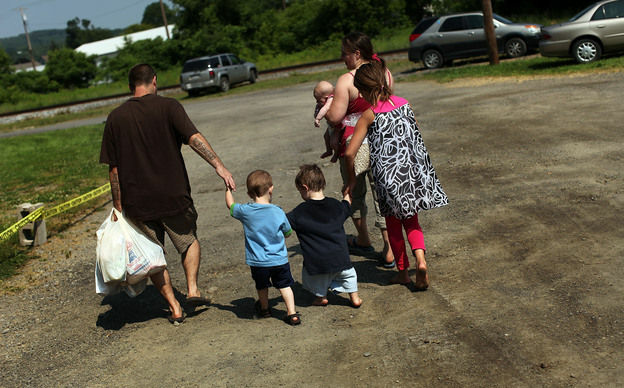 Members of the Dolan family walk home with bags of food from the Food Bank of the Southern Tier Mobile Food Pantry in Oswego, N.Y., in June. Food banks across the nation are reporting giant spikes in demand.