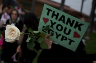 A Syrian woman holds a rose and a sign thanking the people of Egypt for continuing the wave of protests across the Middle East at a demonstration in Irvine, Calif., on May 7.