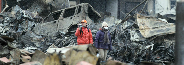 A couple walks under falling snow amongst the rubble in Yamada, Iwate prefecture, on March 15, 2011.