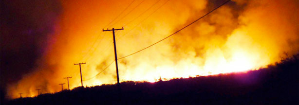 Wildfires fueled by dry conditions have become a common occurrence in Hawaii this summer. Here, a fire lights up the smoke-filled sky in the early hours of May 4, along Honoapiilani Highway in Maui.