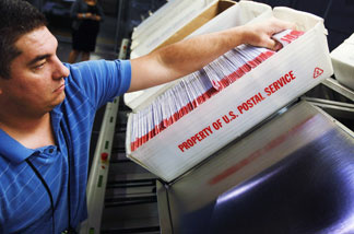 Julio Galligaris sorts through mail-in ballots that have been cast and received at the Miami-Dade Election Department headquarters on Oct. 13 in Doral, Fla.