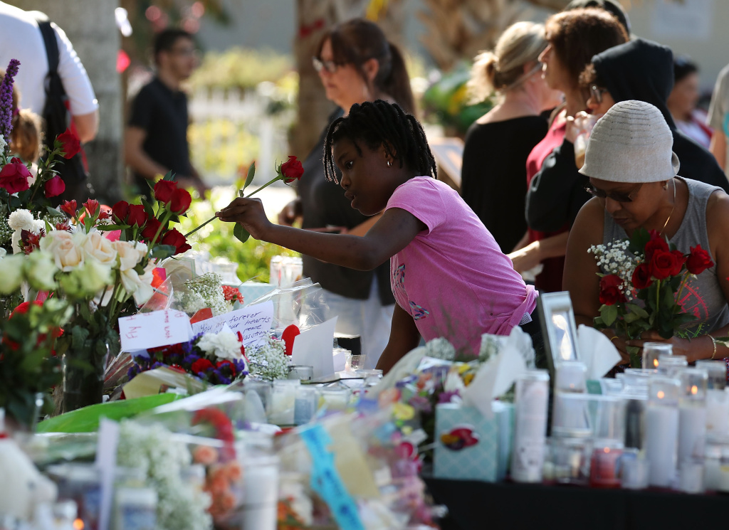 Florida Town Of Parkland In Mourning, After Shooting At Marjory Stoneman Douglas High School Kills 17 People bring flowers to a temporary memorial at Pine Trails Park on February 17, 2018 in Parkland, Florida.