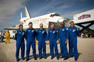 In this handout image provided by NASA, NASA Astronauts and STS-133 mission crew members, from left, Mission Specialists Nicole Stott, Michael Barratt, Pilot Eric Boe, Commander Steve Lindsey, Mission Specialists Alvin Drew, and Steve Bowen pose for a photograph in front of the space shuttle Discovery after they landed at Kennedy Space Center after returning for the last time from a space flight to the International Space Station on March 9, 2011 in Cape Canaveral, Florida.