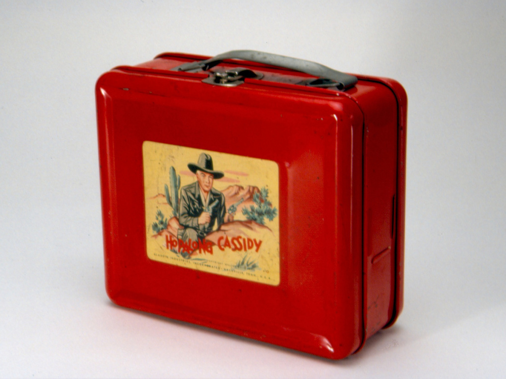 nmah-2004-16238-cea2d5cc54d849a2af0eac5a9cb5859fda039d63-s1200.jpg This steel lunch box, made by Aladdin Industries in 1950, was the first to bear a licensed image, and helped Aladdin launch a new product line that would last for decades. Hopalong Cassidy was a popular TV, radio and comic series.