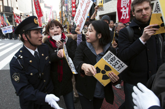 People confront police during an anti-war and anti-nuclear march Sunday, March 20, 2011, in Tokyo. Hundreds of protesters marched for peace and against nuclear power in Tokyo Sunday, as plant workers continue their race to avert disaster at the tsunami-damaged Fukushima Dai-ichi nuclear power plant in the north.