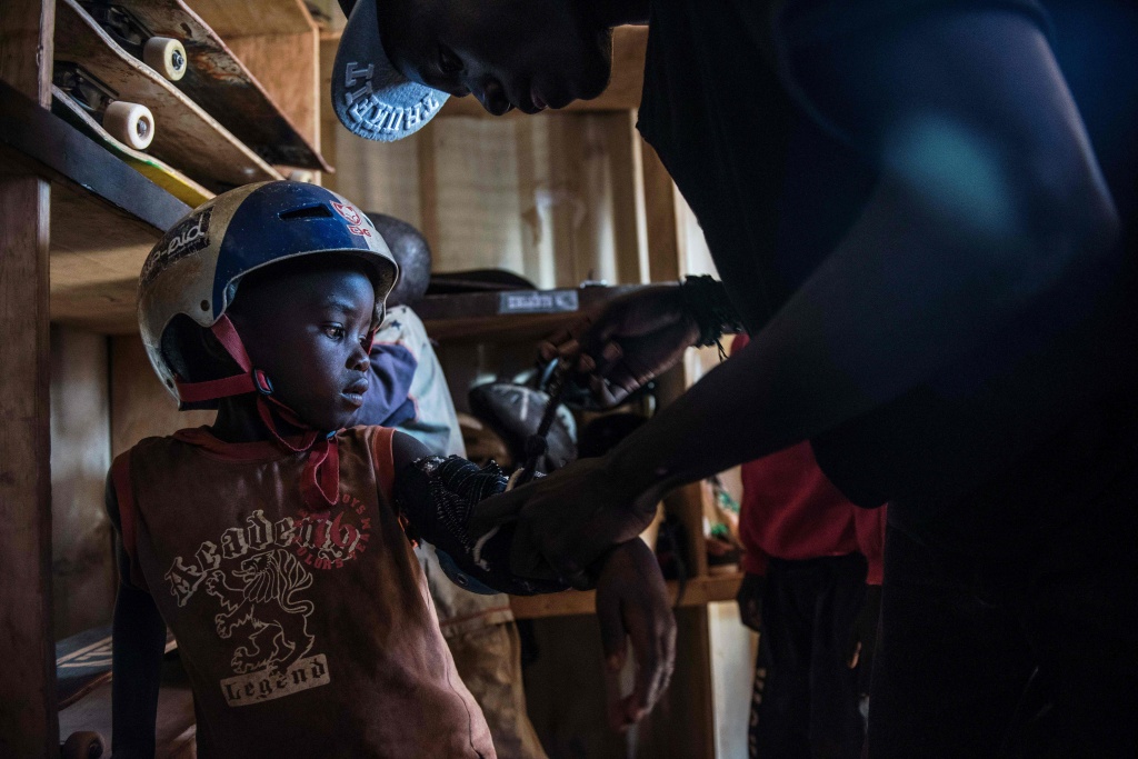 KENYA-FEATURE-SKATEBOARDING Instructor Horace helps young Mickle get his helmet and pads on at Shangilia skatepark in Nairobi on January 13, 2016.