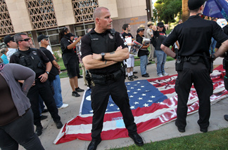 Policemen stand guard over a protesters' flag made by immigrant rights supporters as Arizona conservatives listen to speeches denouncing illegal immigration on July 31, 2010 in Phoenix, Arizona.