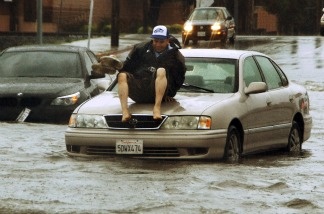 A man gets ready to jump off the hood of his car, stalled on flooded Vineland Ave between Vanowen and Sherman Way in the North Hollywood area of Los Angeles' San Fernando Valley on March 20, 2011. The first day of spring arrived with a bang in Southern California, bringing heavy snow to the mountains and illuminating the sky with flashes of lightning from Santa Barbara to downtown Los Angeles.