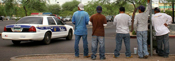 A police cruiser passes by a group of day laborers on a curbside in Phoenix on Monday.