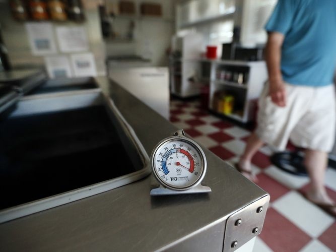 A thermometer reads the temperature atop an empty Maryland ice cream store freezer on Tuesday. Many grocery stores and restaurants are still waiting for power to return for the first time since last weekend's severe storms.