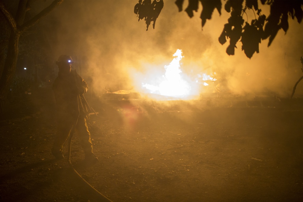 Multiple Wildfires Continue To Ravage Through California Wine Country A firefighter picks up hose next to a burning structure in the early morning hours on October 14, 2017 in Sonoma, California.