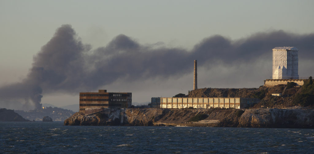 Smoke pours from a fire at the Chevron Richmond Refinery, seen behind Alcatraz Island in San Francisco, Monday, Aug. 6, 2012. Officials have told residents of two Northern California cities to shelter-in-place as a fire at the refinery releases plumes of black smoke. The fire, first reported at 6:40 p.m. Monday, is burning in a process unit at the refinery, officials said. It was sending smoke over the cities of Richmond and San Pablo. (AP Photo/Eric Risberg)