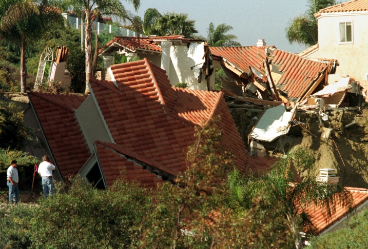 1938: People walk along the flooded L.A. River near the Dayton Avenue Bridge. In the background, a railroad bridge hangs in a twisted heap after one of the pilings has collapsed. (Photograph courtesy of the Los Angeles Public Library)