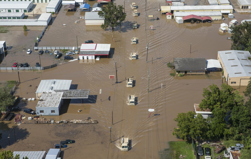 Harvey National Guard vehicles drive down a flooded street in Wharton, Texas, on Friday.