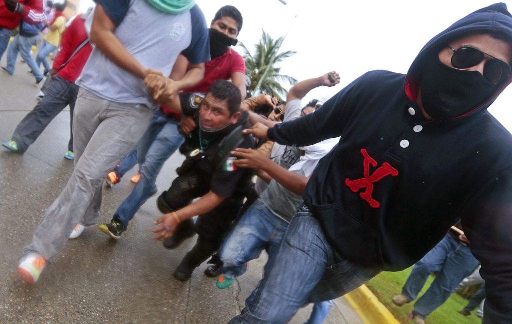 MEXICO-CRIME-STUDENTS-PROTEST Demonstrators hold a riot police during clashes following a protest against the suspected massacre of 43 missing students, near the airport in Acapulco, in the Mexican state of Guerrero State, on November 10, 2014.