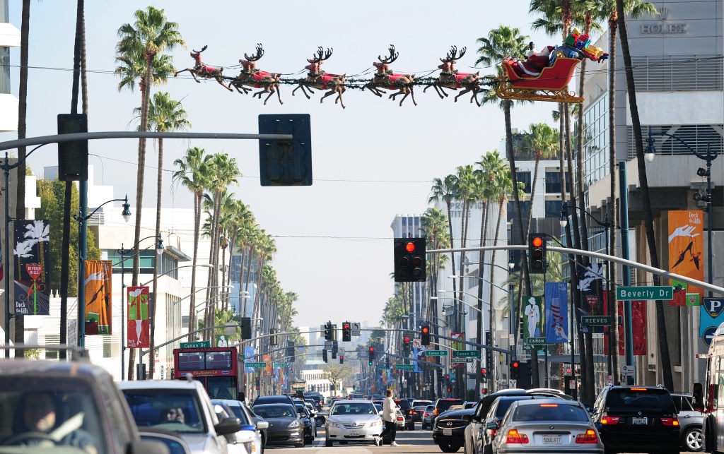 Traffic flows along Wilshire Boulevard i Traffic flows along Wilshire Boulevard in Beverly Hills beneath suspended lifesize figures of Santa Claus delivering toys, 2011.