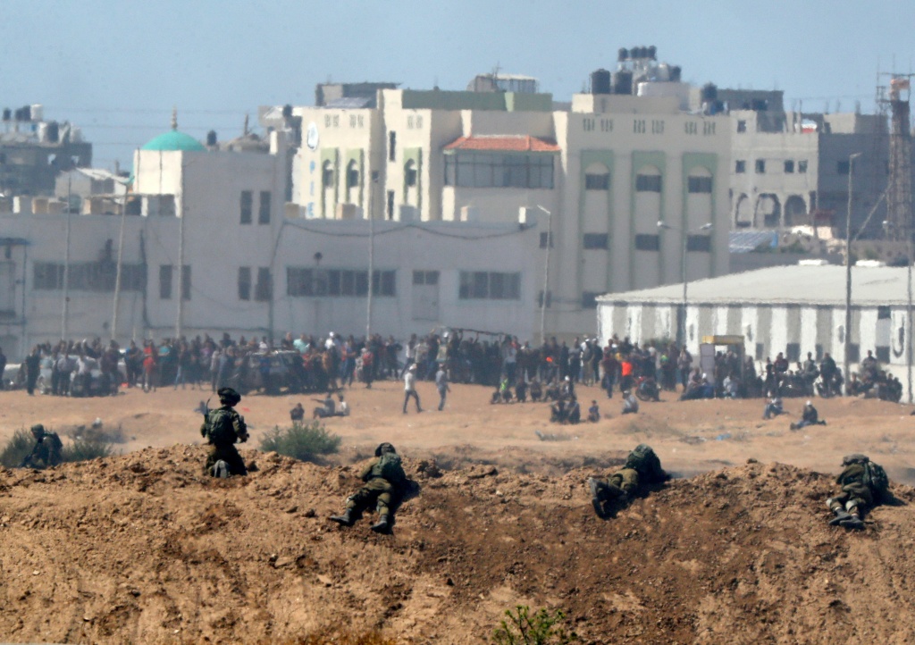 A picture taken on May 14, 2018 from the southern Israeli kibbutz of Nahal Oz across the border with the Gaza Strip shows Israeli soldiers keeping position and Palestinian protesters gathering along the border fence with Israel. A picture taken on May 14, 2018 from the southern Israeli kibbutz of Nahal Oz across the border with the Gaza Strip shows Israeli soldiers keeping position and Palestinian protestors gathering along the border fence with Israel.