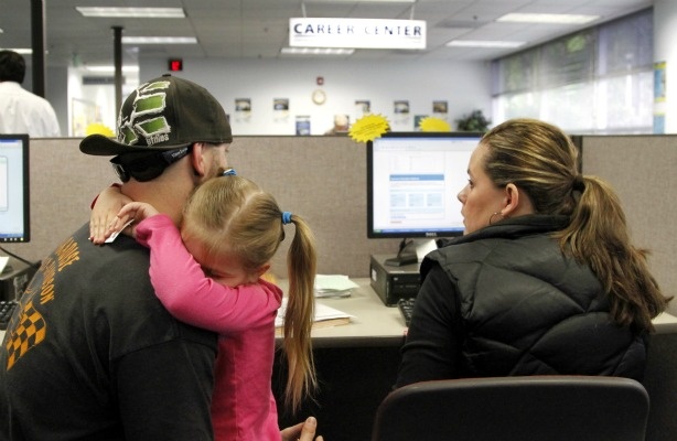 Mercer 18972 In this photo taken June 14, 2011, Matthew Weisker, left, holds his four-year-old daughter, Lexi Weisker, as he and his wife, Mindy, look for jobs in the database at Worksource Oregon in Tualatin, Ore.