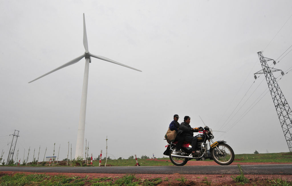 TO GO WITH China-Energy-Environment-Wind In a picture taken on June 16, 2009, commuters on a country road ride past a wind farm developed by state-owned China Energy Conservation Investment Corp in Zhangbei, north of Beijing in Hebei province. While a couple of years ago only a few dozen of the 80-metre (262-foot) propellor-like turbines stood on the wind farm's vast open expanse of grass, today there are 200 and counting.