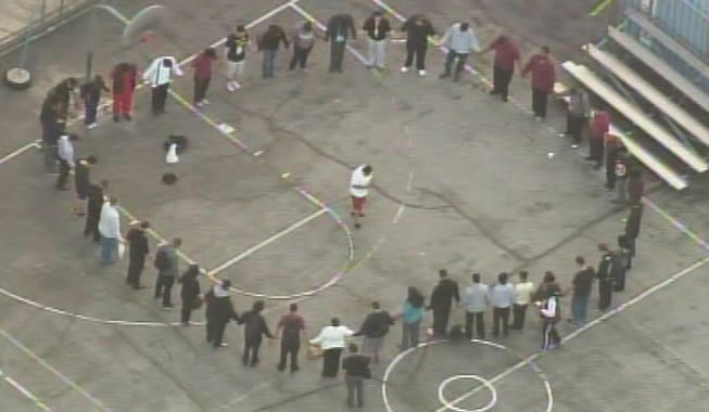 A group holds hands in a circle on the grounds of a Hollywood school where a counselor was fatally stabbed.