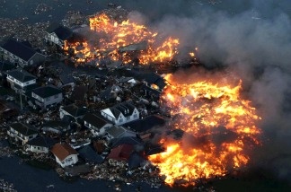 This aerial shot shows houses in flame after being hit by a tsunami at Natori city in Miyagi prefecture, northern Japan on March 11, 2011.