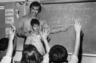 Mercer 19001 A teacher points to the blackboard at Belvedere Elementary School as students raise their hands.