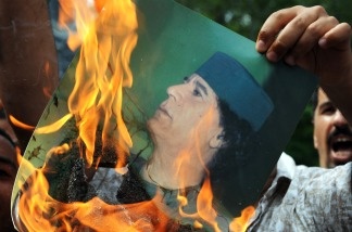 Mercer 15264 A Libyan protester burns a portrait of Libyan leader Moamer Kadhafi in front of the Libyan embassy in Kuala Lumpur on February 23, 2011. Some 200 protesters gathered in front of the embassy with banners and placards to condemn the bloody crackdown on anti-government demonstrators in Libya.
