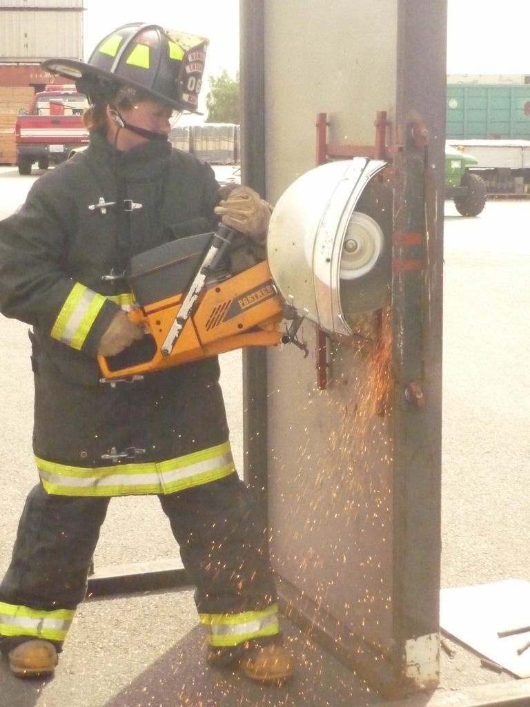 A Mexican firefighter practices using a rotary saw at an angle to cut open an iron door. Los Angeles City firefighters covered the technique, along with other related material, in a free two-day workshop at their headquarters near Dodger Stadium.
