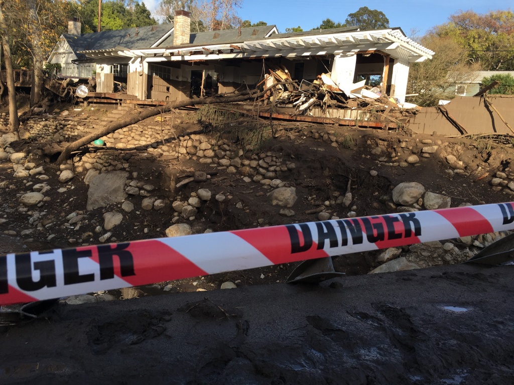 Mud line on white house in Montecito mud flow Warning tape blocks a damaged bridge on East Valley Road over Montecito Creek, while behind the creek, a brown mud line on the white house shows how high the debris flowed during the Jan. 8, 2018 rainstorm and flood.