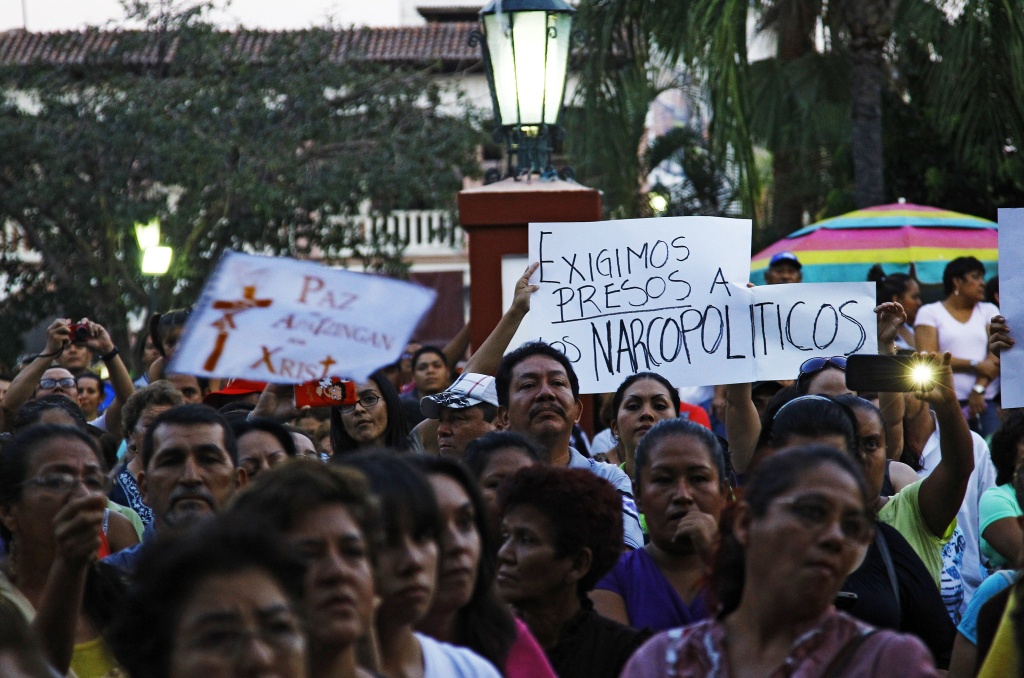 MEXICO-VIOLENCE-MICHOACAN-MARCH People hold a sign reading 'We demand narco-politicians to be jailed' as they take part in a march for peace in Apatzingan, Michoacan State, Mexico, on January 18, 2014. Federal forces in recent days have moved into Michoacan, in western Mexico, and tried to disarm the local vigilante groups and flush out the Knights Templar drug trafficking gang, which has seized control of large swathes of this state.
