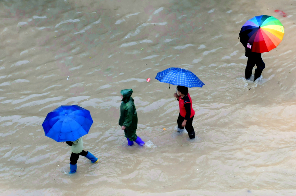 CHINA-PHILIPPINES-WEATHER-TYPHOON Pedestrians make their way across a street flooded by rains brought by Typhoon Haiyan in Shangsi, in southwest China Guangxi province on November 11, 2013. At least six people died after Typhoon Haiyan slashed across China's south coast and damaged hundreds of homes, state-run media on November 11, just days after devastating the Philippines over the weekend.