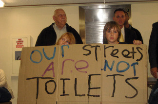 Residents at Venice forum hold up "Our Streets Are Not Toilets" sign.