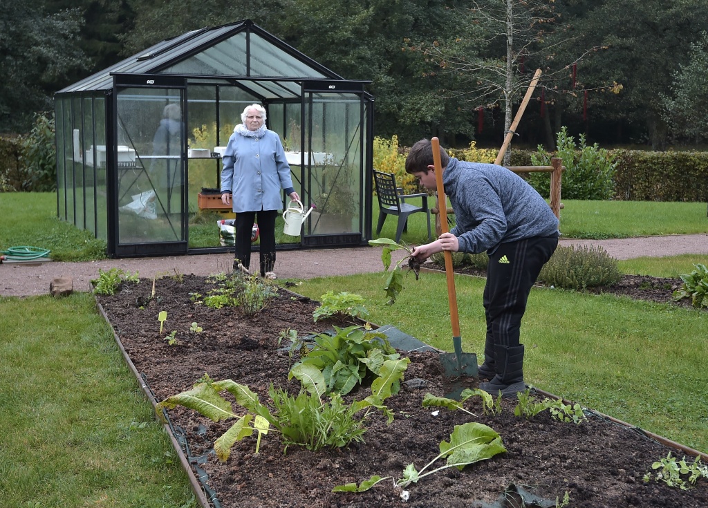 FRANCE-HEALTH-EDUCATION-ALZHEIMER A woman with Alzheimer's disease holds a watering can as a teenager works in the garden of a retirement home on October 18, 2016 in Saint Quirin, France.