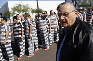 Inmates walk as they are moved after being ordered by Maricopa County Sheriff Officer Joe Arpaio (R), looking on, to be placed into new housing to open up new beds for maximum security inmates on April 17, 2009 in Phoenix, Arizona.