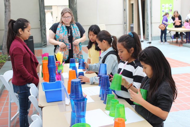 Children’s librarian Brooke Sheets (center) uses colored cups to teach algorithms and debugging to a group of girls at a computer science fair at L.A.'s downtown Central Library