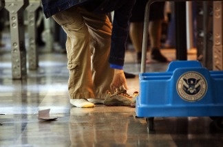 Mercer 11578 A passenger removes their shoes before passing through the passenger security checkpoint at John F. Kennedy International Airport in New York City.