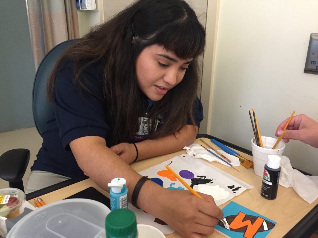 Volunteer Jessica Ortiz helps Rosanna make a coaster. Volunteer Jessica Ortiz helps Rosanna make a coaster.