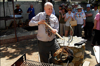 Mercer 7682 Charles Perry, L.A. Times food writer and President of the Culinary Historians of Southern California, lifts a hunk of beef from the pit in which it's been cooking for half a day.