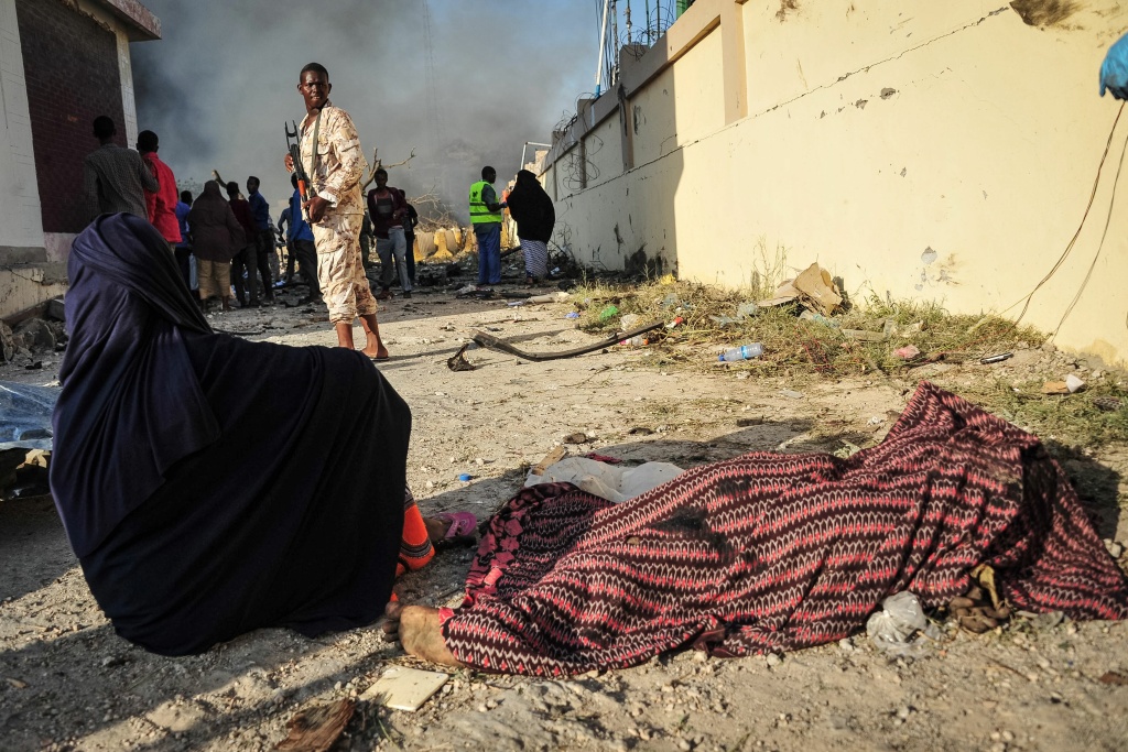 SOMALIA-BOMBINGS-CONFLICT A woman sits by the body of a victim near the site where a truck bomb exploded in the center of Mogadishu on October 15, 2017.
