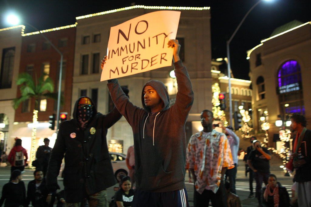 Protesters In LA React To Grand Jury Decision In Ferguson Case 

 LOS ANGELES, CA - NOVEMBER 24: Protesters shut down traffic by blocking the intersection of Wilshire Boulevard and Rodeo Dr. in Beverly Hills after marching from Leimert Park in reaction to the grand jury decision not to indict a white police officer who had shot dead an unarmed black teenager in Ferguson, Missouri on November 24, 2014 in Los Angeles, California. Police officer Darren Wilson shot 18-year-old Michael Brown on August 9, sparking large ongoing protests. (Photo by David McNew/Getty Images)
