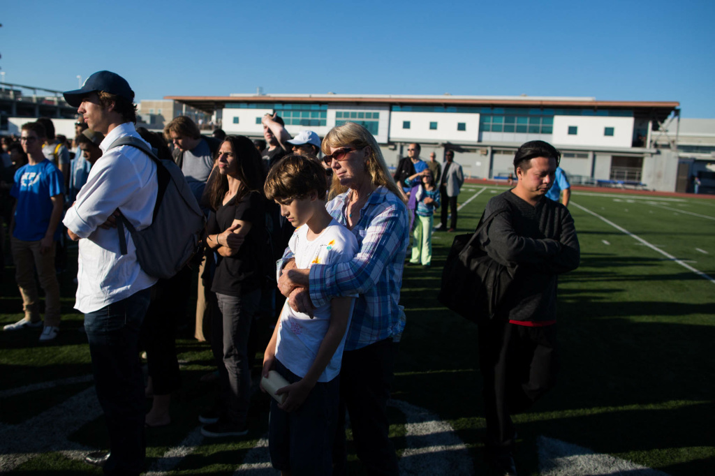 Mourners watch a vigil for five people killed in a mass shooting that ended at Santa Monica College.