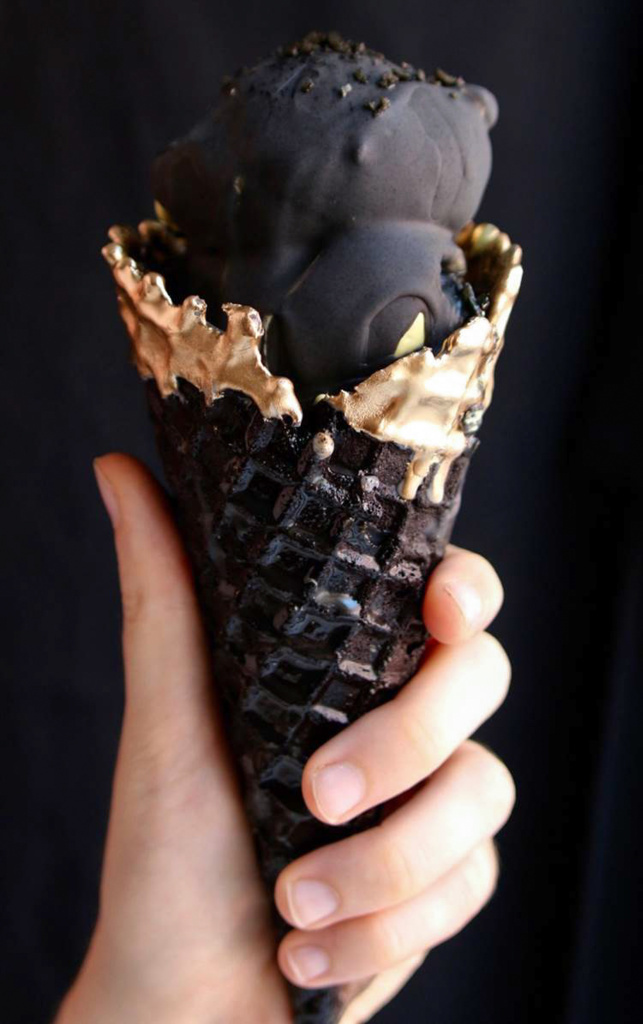 The Eclipse Magic Cone features a black waffle cone made with coconut ash and tipped with edible gold, and an interior filled with spiced marshmallow fluff and a golden-yellow ice cream flavored with ginger and turmeric.