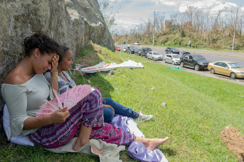 Puerto Rico Hurricane Kiara Rodriguez de Jesus, 23, (left) and friend Stephanie Norat, 26, find shade as people wait in line at the Gulf Route 65 gas station for a gasoline tanker scheduled to arrive.